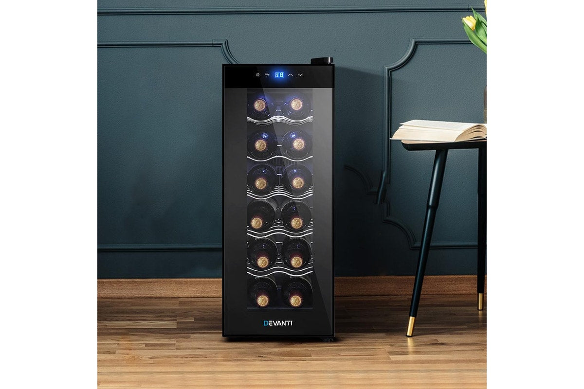 A black Devanti wine cooler with a glass door, shown standing on a wooden floor against a dark teal paneled wall. The cooler is stocked with wine bottles and has a blue digital display on the top door.