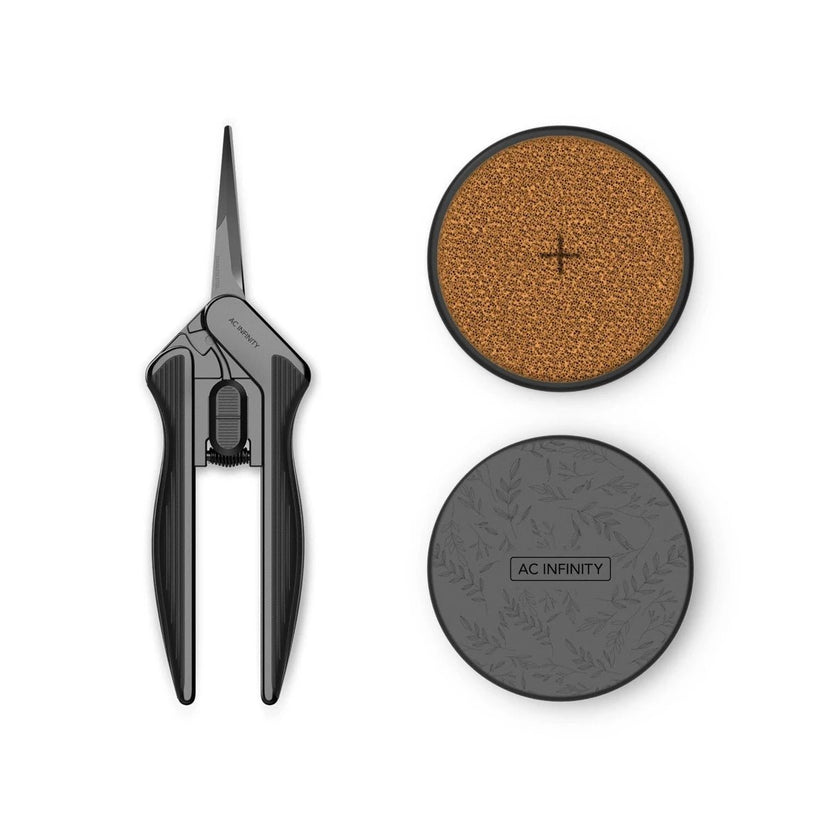 AC Infinity folding scissors with black handles, shown open next to two circular accessories: a textured brown pad with a cross symbol and a dark gray round case embossed with leaves and labeled AC INFINITY.